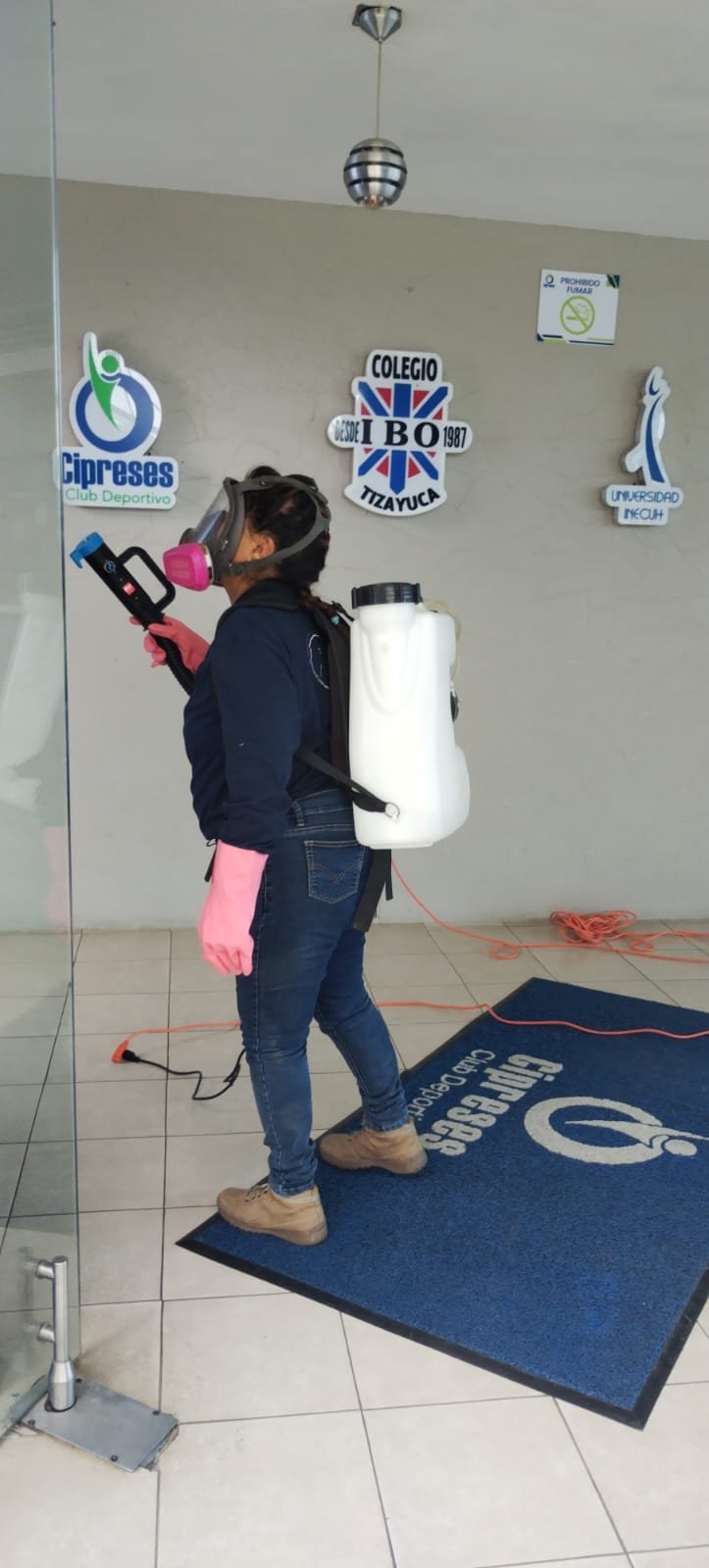 Técnica PlaguiBio con equipo de aspersión fumigando interior de un colegio